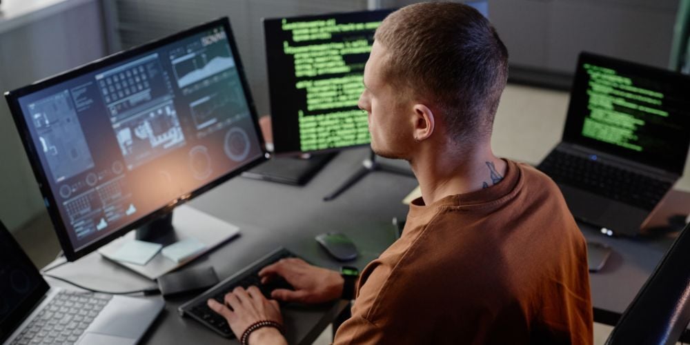A cybersecurity analyst monitoring multiple screens, evaluating if SIEM is essential for protecting a small business network.