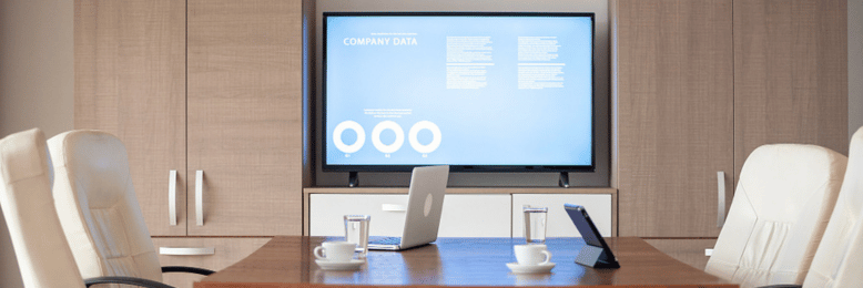 A modern conference room design featuring a wooden table, white leather chairs, and a large screen displaying company data.