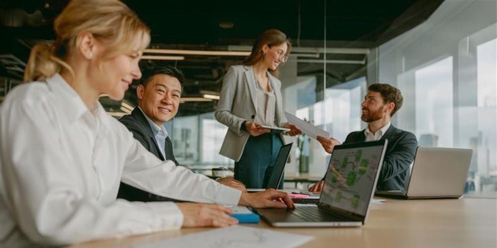Business professionals collaborating in a modern office and reviewing IT strategy on laptops, highlighting the value of treating technology as a business investment