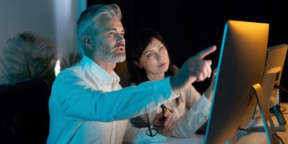 Business professionals discussing IT strategy at a desktop, representing managed service providers vs. software vendors.