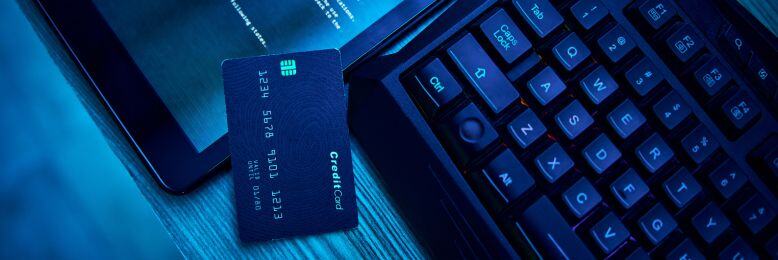 Cybersecurity setup with credit card and computer screens, illustrating challenges in PCI DSS compliance