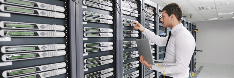 Technician checking data backup servers with a laptop in data center