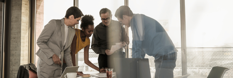 Diverse team analyzing documents on IT plans at a bright office desk