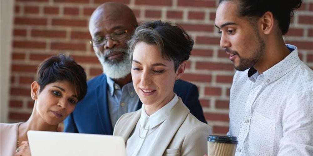 Diverse team reviewing information on a laptop, symbolizing collaborative efforts to prepare for a CMMC assessment and understand cybersecurity compliance requirements