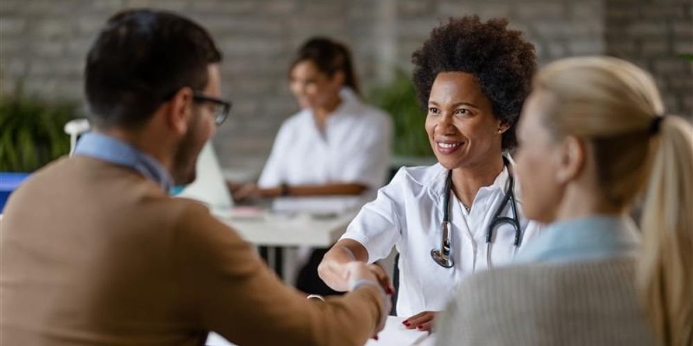 Doctor greeting patients in a clinic, representing the human side of HIPAA certifications vs. HIPAA compliance