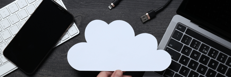 Hand holding a paper cloud against a tech setup, representing cloud services for large file transfers