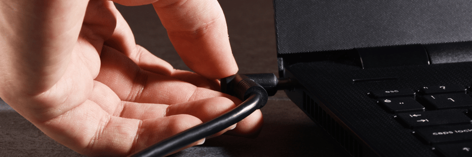 Hand plugging the charger to the laptop