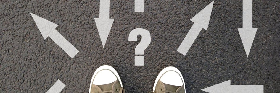 a pair of shoes facing a question mark and arrow signs painted on the road