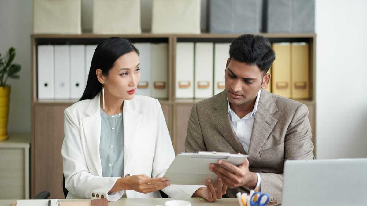 Two colleagues reviewing documents together in an office