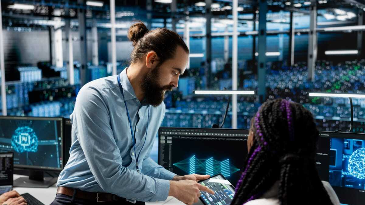 IT team lead guiding a colleague in a data center