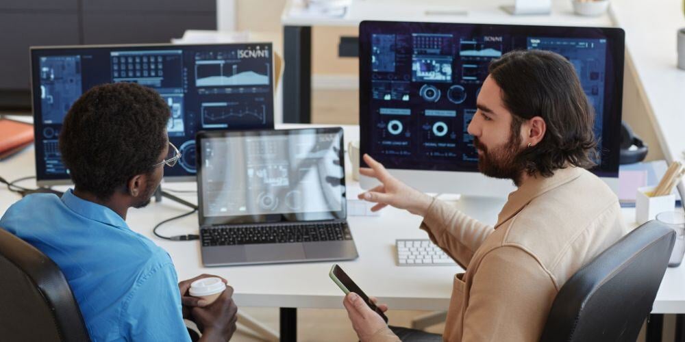 IT specialists analyzing system data on multiple screens, illustrating the roles of software vendors and managed service providers.