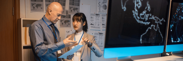IT specialists discussing network assessment results next to monitoring screens