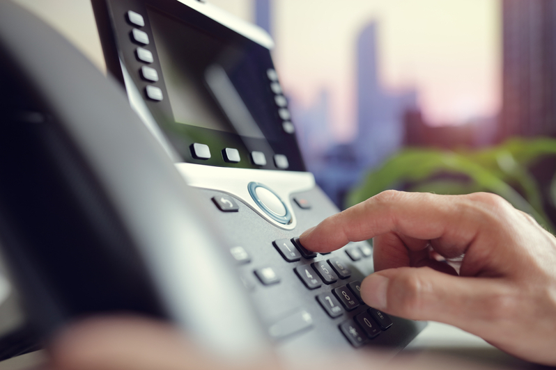 A hand dialing numbers on VoIP phone