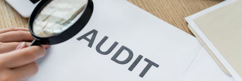 Magnifying glass focusing on AUDIT text, symbolizing the detailed scrutiny in SOC 2 audits