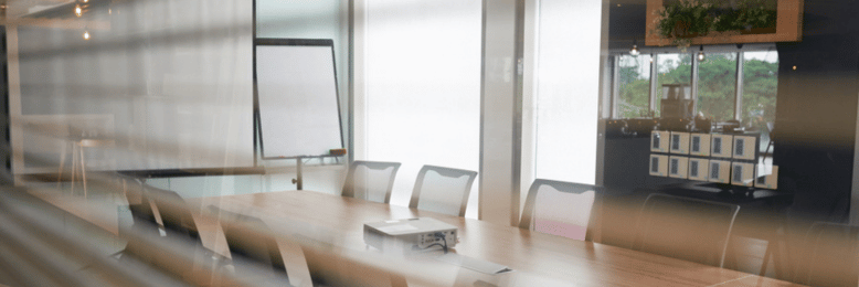 Modern conference room design with wooden table, chairs, whiteboard, and large windows.