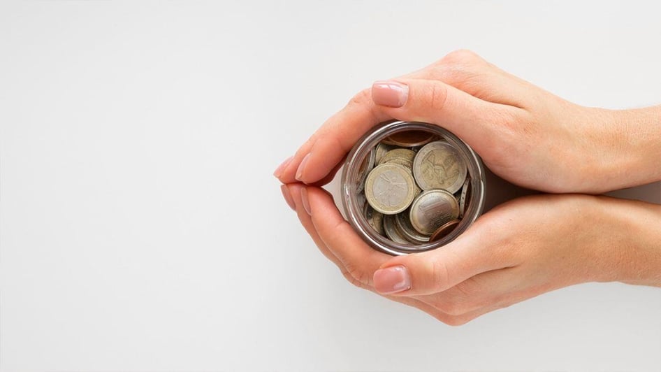 a hand holding a jar full of coins depicting a tight budget for cybersecurity