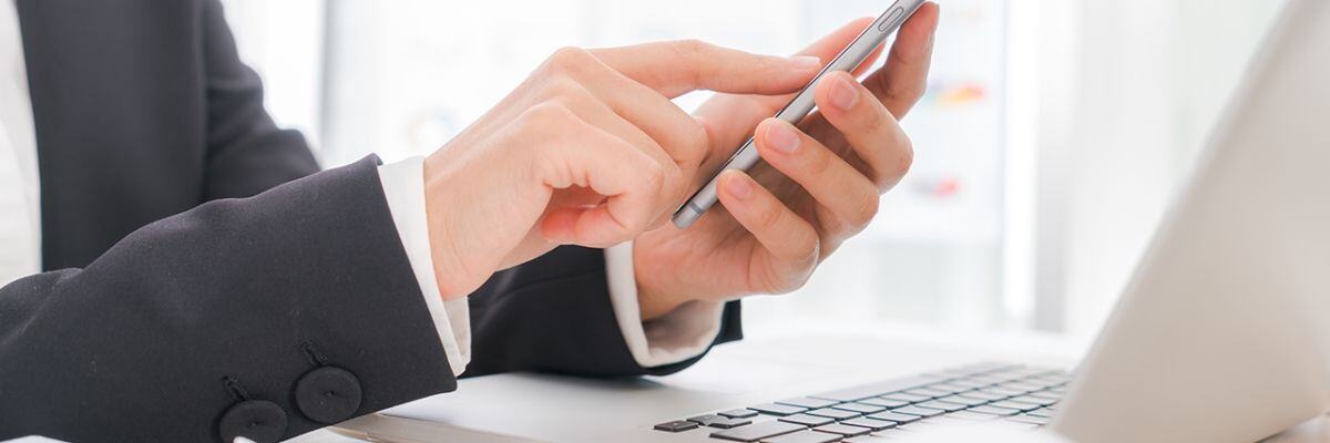 a person holding a phone in front of a laptop