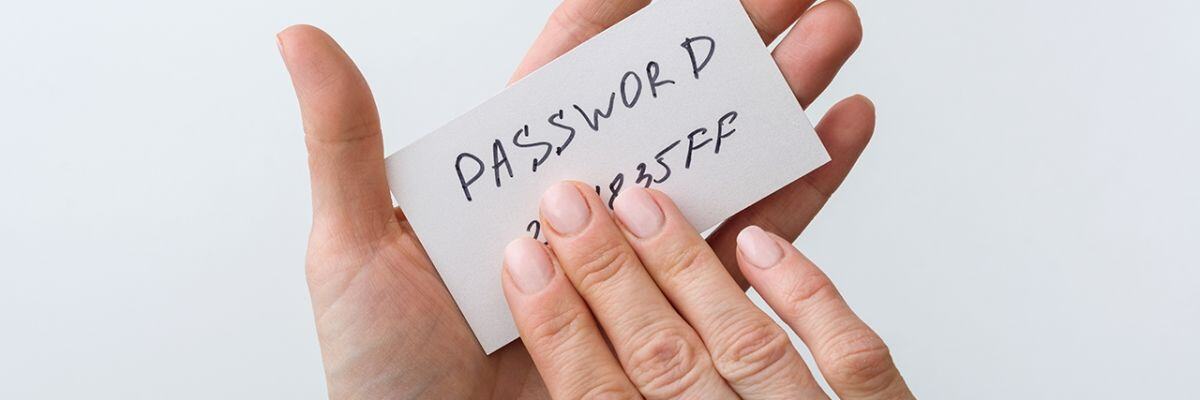 A hand holding a password written on a piece of paper