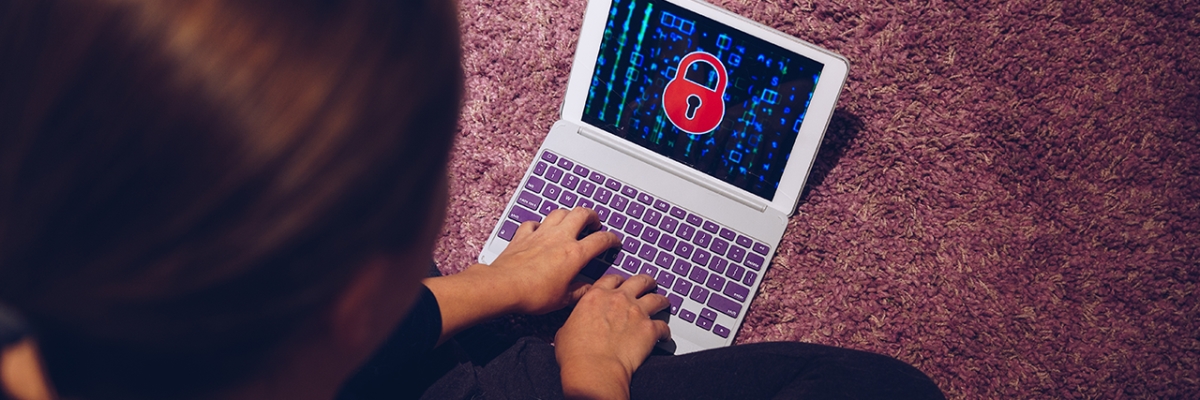 Person using a laptop displaying a ransomware lock symbol, indicating a security breach 