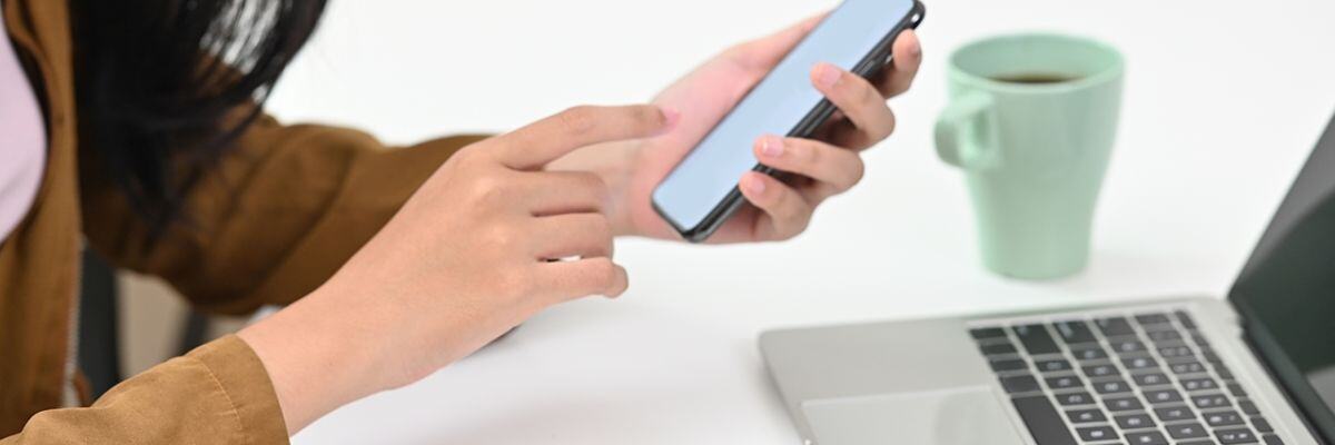 a female holding a phone in front of laptop