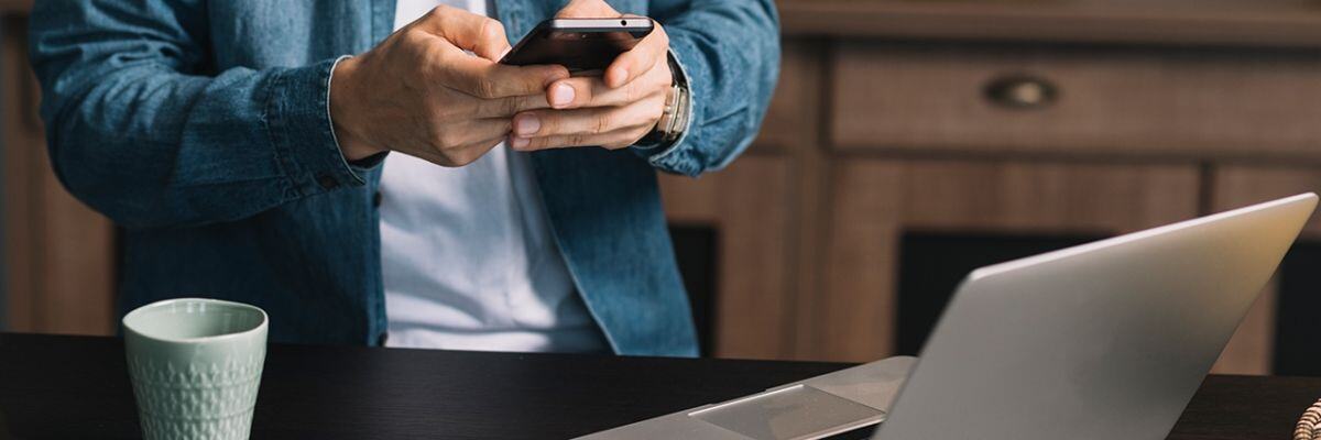 A person holding a phone in front of the laptop