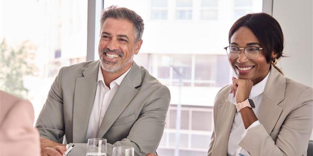 Professionals in a meeting smiling and collaborating, emphasizing the advantages of outsourced IT for FAR compliance efficiency