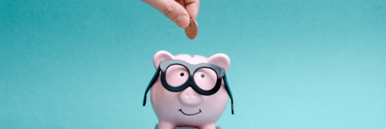 Save money - coin being dropped on a piggy bank