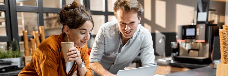 Small business owner and IT technician discussing in front of a laptop