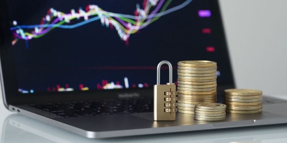 Stacked coins and a combination padlock on a laptop, symbolizing cybersecurity investment and the financial cost of protecting digital assets