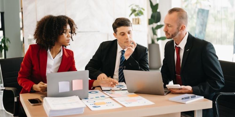 Team of executives in discussion over data charts and laptops, exploring how strategic IT investments drive smarter business decisions