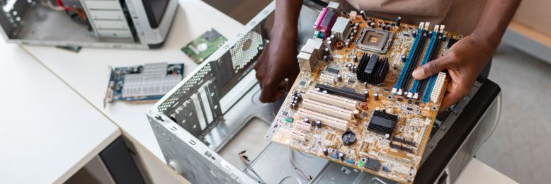 Technician examining computer motherboard during a hardware disposal process