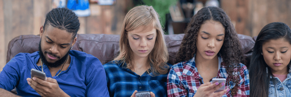 Teens sitting together using smartphones