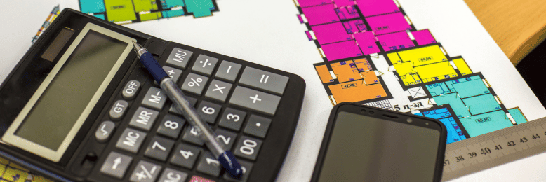 Workspace with calculator and architectural plans, analyzing managed IT expenses