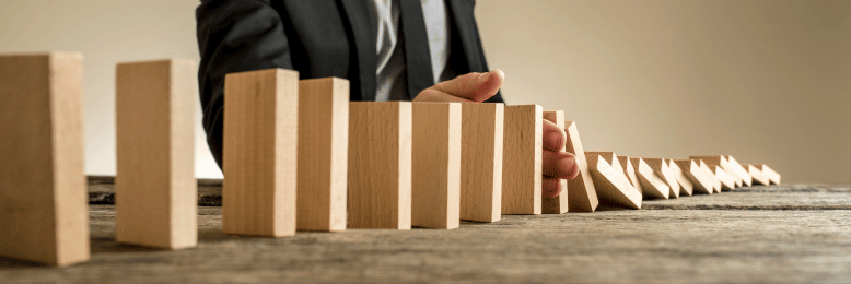 a person stopping a domino collapse