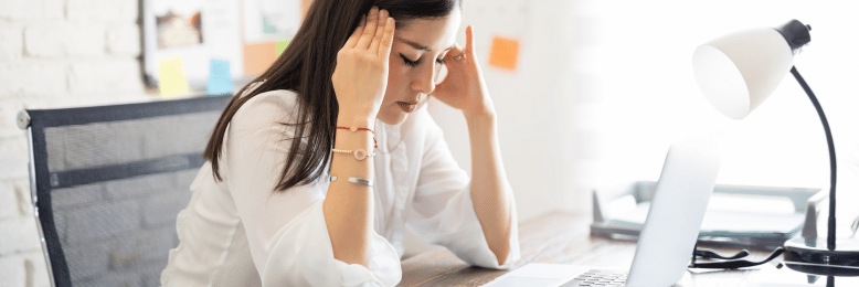 a person with a headache in front of a laptop