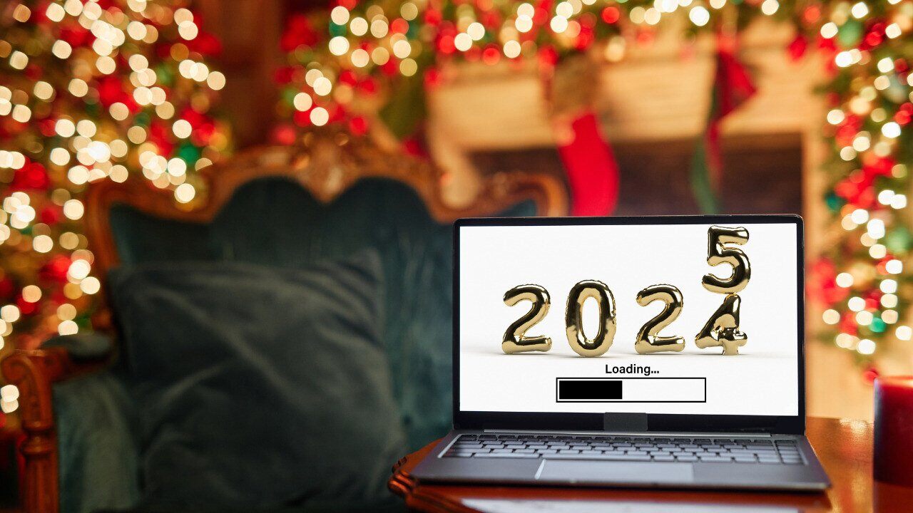 A cozy holiday-themed setting featuring a laptop on a table. The laptop screen displays gold numbers transitioning from 