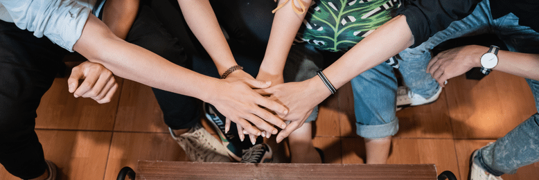 four people with their hands together