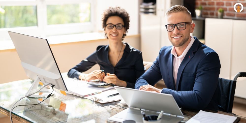 two employees sitting on the desk infront of the computer reviewing compliance of FTC safeguard rules by an auto dealership