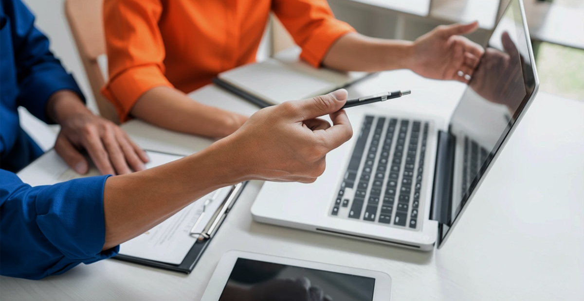 Two professionals reviewing documents and a laptop during a managed IT services onboarding and business planning meeting.