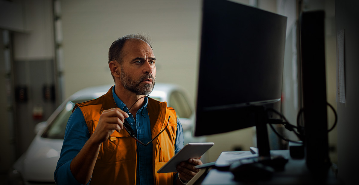Automotive technician reviewing system alerts on computer, highlighting common managed IT problems in auto dealerships.