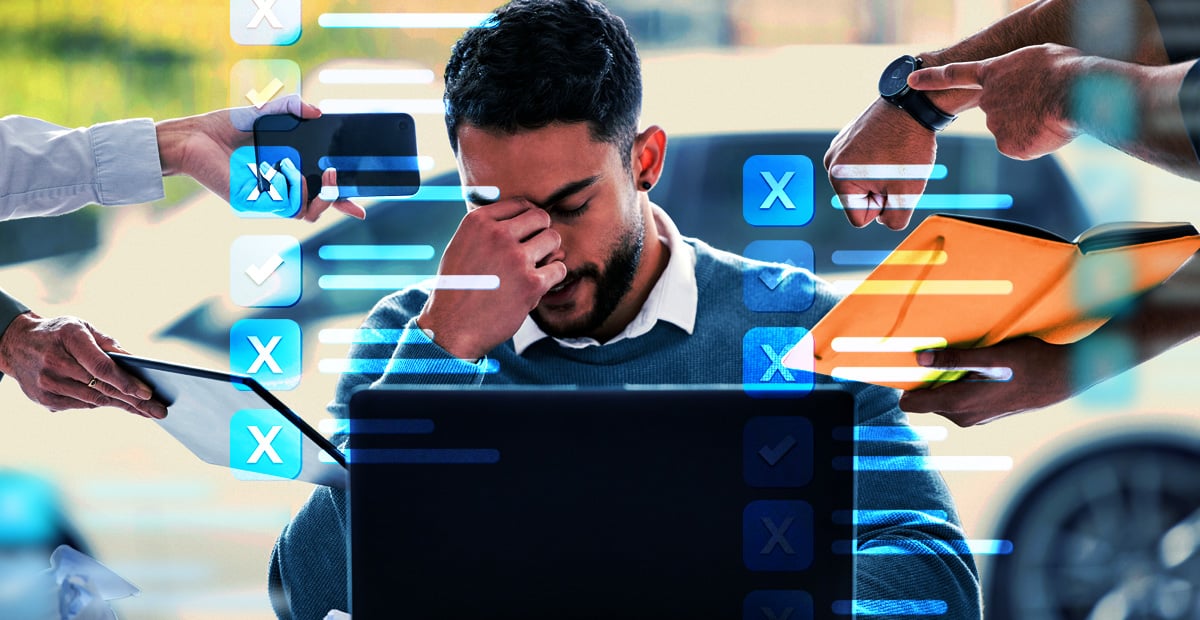 Auto dealership employee overwhelmed by OEM cybersecurity compliance tasks, illustrating challenges with automotive cyber rules.