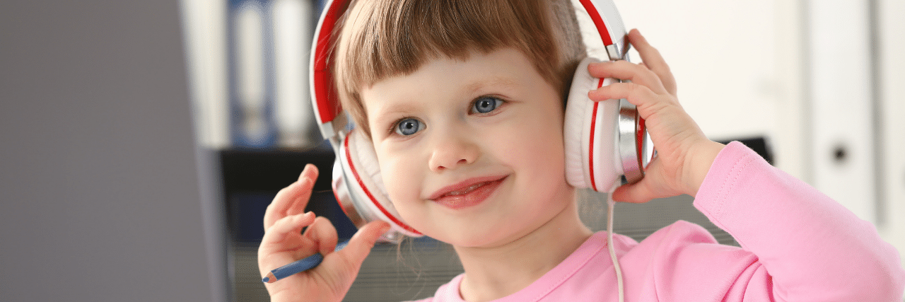 Happy young girl on headset and using a computer