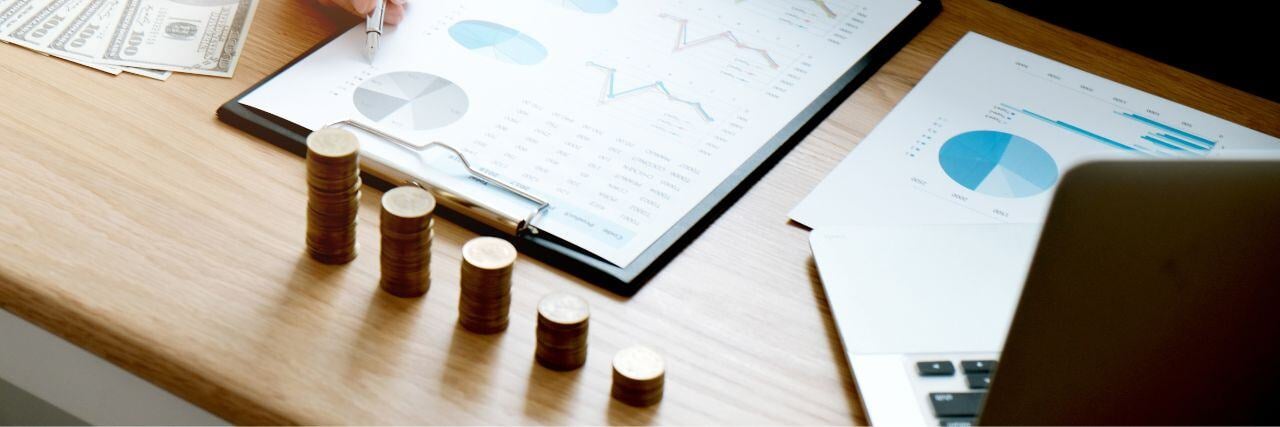 a series of coins on the table with a person working on the compliance report