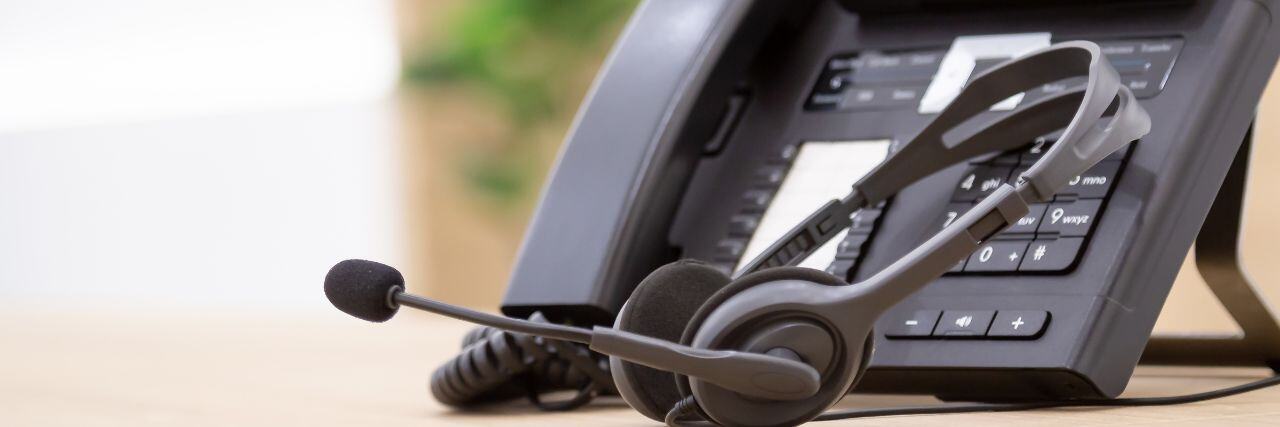 a headset beside a landline on top of a table