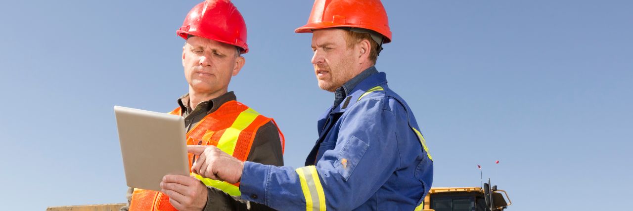two person wearing hard hats discussing hiring an IT company