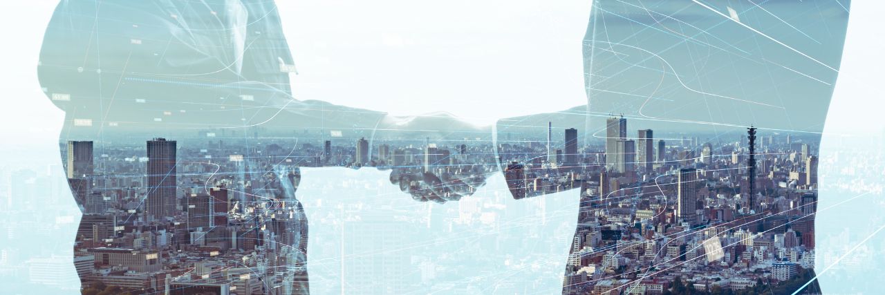 two people shaking hands with the silhouette of buildings on the back