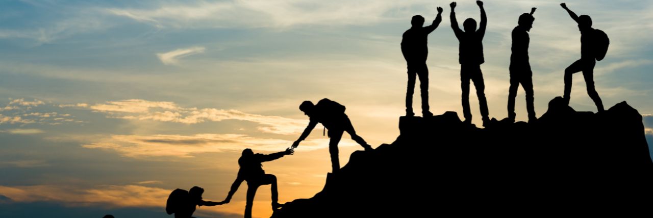 A group of hikers helping each other climb the top like how Managed IT can help your business grow