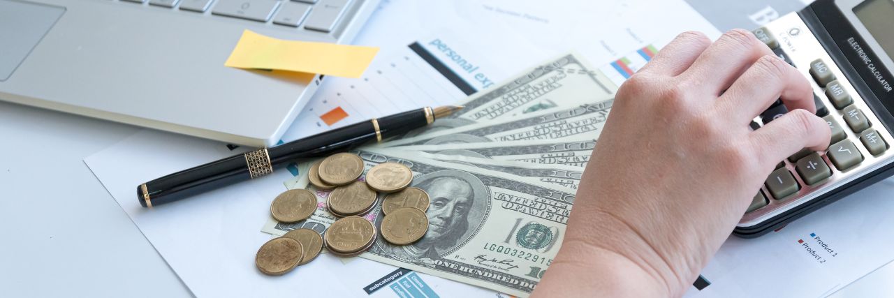 person in front of laptop with money and calculator