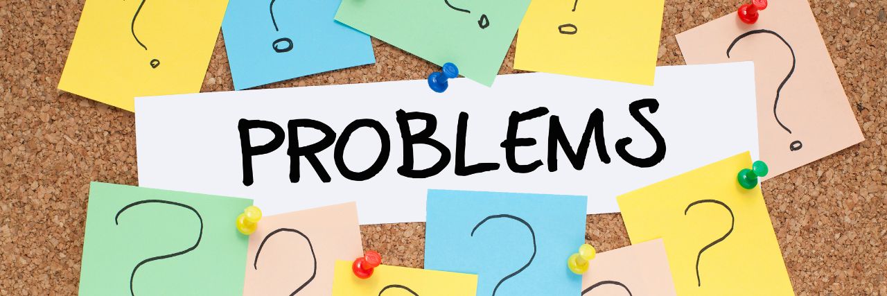 problems written on a bulletin board surrounded by question marks written on post its