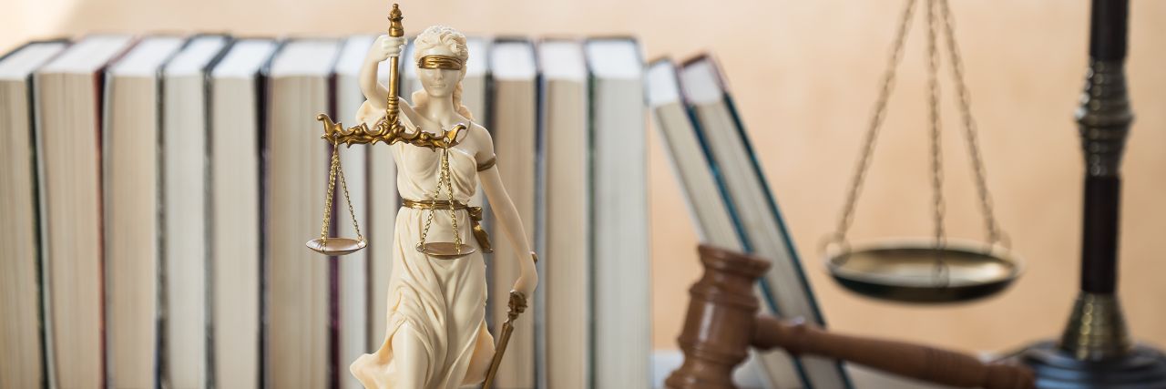 the lady of justice with law books and gavel in the background